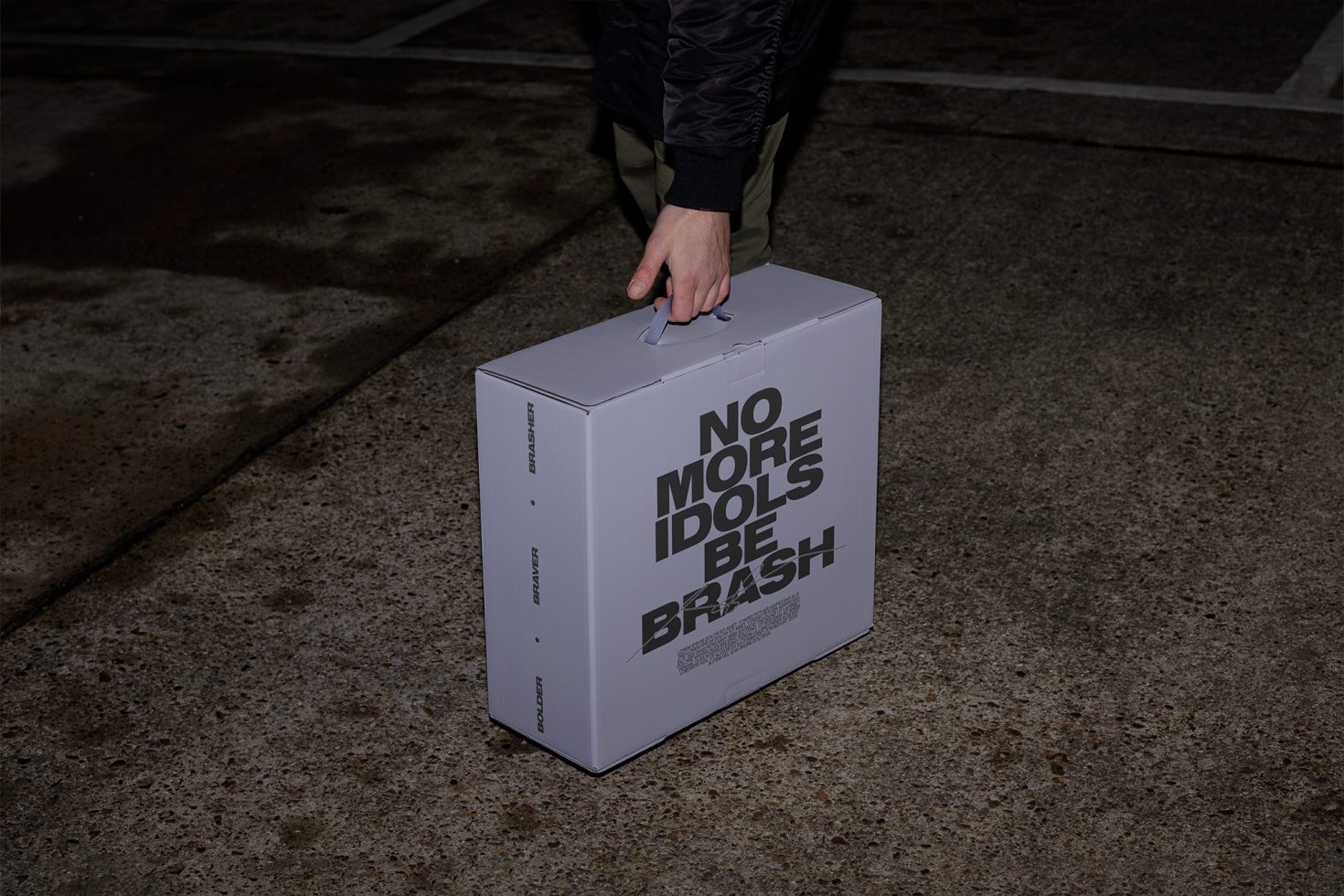 Person holding a product box with bold typography design, ideal for packaging mockup graphics on digital asset marketplace for designers.